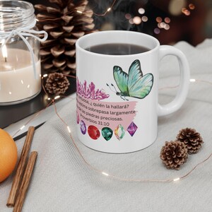 Puede incluir: Taza de cerámica blanca con un diseño de mariposa y piedras preciosas de colores. La taza tiene una cita de Proverbios 31:10 que dice: "Virtuosa, ¿quién la hallará?  estima sobrepasa largamente delas piedras preciosas.  Proverbios 31:10"
