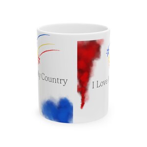 Puede incluir: Taza de cerámica blanca con un diseño de acuarela rojo, blanco y azul. La taza tiene el texto "I Love My Country" en el lado derecho y "My Country" en el lado izquierdo.