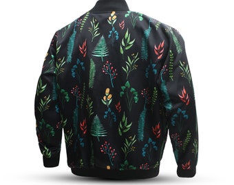 Puede incluir: Una chaqueta bomber negra con estampado floral con flores verdes, rojas y amarillas. La chaqueta tiene cierre de cremallera y puños y cintura de canalé.