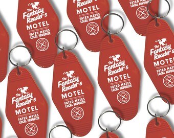 May include: A collection of red, diamond-shaped motel-style keychains featuring a white dragon graphic and the text The Fantasy Reader's MOTEL, FATED MATES, LOCAL FAVORITE, and a circular logo with the text ONE MORE CHAPTER.