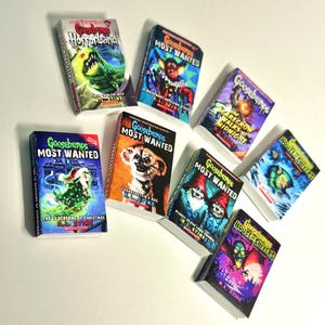 Peut inclure: Une collection de livres miniatures Goosebumps, avec des titres tels que "HorrorLand" et "House of Shivers". Les livres ont des couvertures color&eacute;es avec des illustrations de monstres et de sc&egrave;nes effrayantes. Le nom de l'auteur, R.L. Stine, est visible.