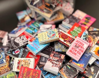 May include: A collection of miniature books with colorful covers, including titles like "Pride and Prejudice" and "1984." The books are scattered around a clear jar, creating a visually appealing arrangement. The books vary in size and design.