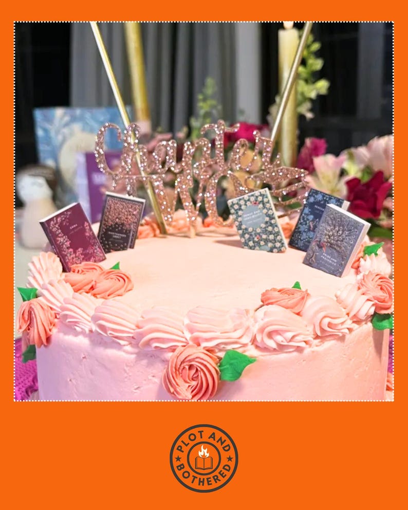 Peut inclure: Un g&acirc;teau rose d&eacute;cor&eacute; de tourbillons de gla&ccedil;age roses et de d&eacute;corations de livres miniatures. Un cake topper en or rose indique "Chapitre 30". Le g&acirc;teau est entour&eacute; de fleurs et de bougies.