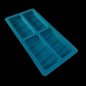 Może przedstawiać: Turkusowa, prostokątna tacka na kostki lodu z ośmioma prostokątnymi przegródkami. Na tacy znajduje się napis "THE BIG ZANNY". Taca wykonana jest z elastycznego materiału i umieszczona na czarnym tle.