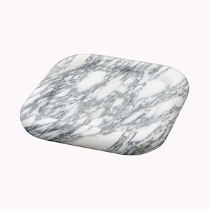 May include: A white marble tray with grey veining. The tray has a slightly rounded rectangular shape and a shallow well in the centre.