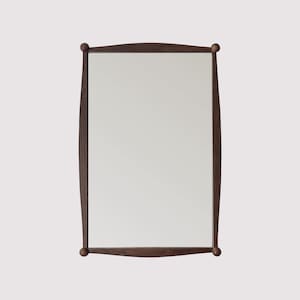 May include: A dark brown wood framed mirror with rounded edges and a simple design.