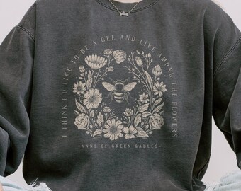May include: A black sweatshirt with a floral design and a bee in the center. The text on the sweatshirt reads "I think I'd like to be a bee and live among the flowers - Anne of Green Gables - "