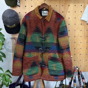 May include: A multi-colored wool coat with a geometric pattern, featuring a brown corduroy collar and toggle closures. The coat has two front pockets and a label that reads "Lakeside".