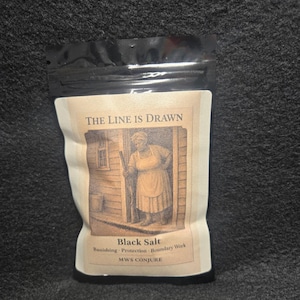 May include: A black pouch of black salt with a label featuring an illustration of a woman in a doorway. The label reads "The Line Is Drawn" and lists "Banishing, Protection, Boundary Work" and "MWS CONJURE".