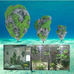 Puede incluir: Tres decoraciones artificiales para acuario con forma de islas flotantes. Las islas son grises con musgo verde y tienen una base negra. La imagen también muestra las decoraciones en un acuario con peces y plantas.