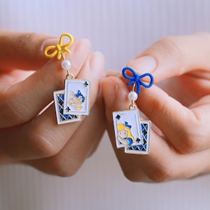 Jolies boucles d'oreilles Alice au pays des merveilles avec chat du Cheshire | Cartes de poker asymétriques pendantes. Puces d'oreilles amusantes avec un nœud délicat