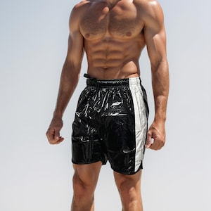 May include: A black and white athletic short with a white stripe down the side. The short is made of a shiny, wet-look material.