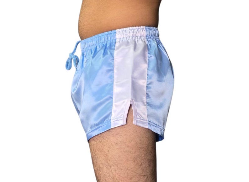Puede incluir: Shorts de sat&eacute;n azul claro con una franja vertical blanca en el lateral. Los shorts tienen cintura con cord&oacute;n y abertura en el dobladillo. La tela tiene un ligero brillo. Estilo retro.