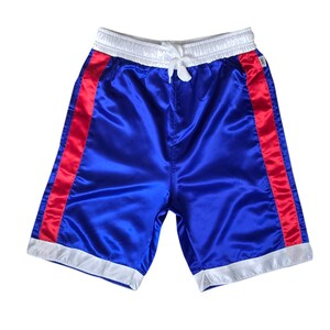 K&ouml;nnte beinhalten: Blaue Satin-Shorts mit roten und wei&szlig;en Biesen. Die Shorts haben einen wei&szlig;en Bund und einen Kordelzug.