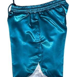 May include: Teal satin shorts with a drawstring waist and white trim along the bottom hem. The shorts have a shiny, reflective surface. The garment is designed for comfort and style.