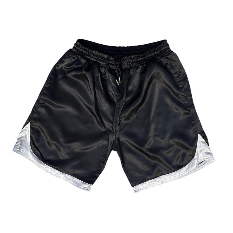 May include: Black satin shorts with a drawstring waist and white trim. The shorts have a shiny finish and a casual style. The shorts are a solid colour and are suitable for athletic activities or casual wear.