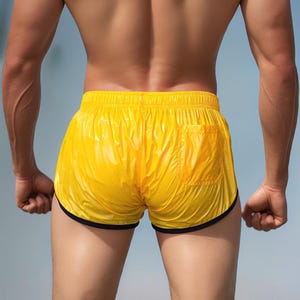 Op de afbeelding: Felge gele sportbroek met een zwarte bies. De short heeft een enkele zak aan de achterkant en is gemaakt van een glanzend, lichtgewicht materiaal. De short wordt van achteren getoond.