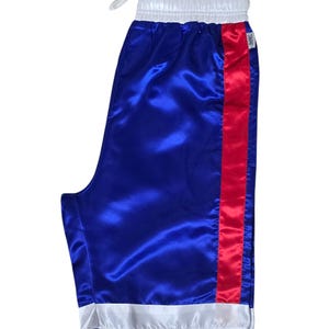 K&ouml;nnte beinhalten: Blaue Satin-Boxershorts mit einem roten Streifen an der Seite und wei&szlig;em Besatz an Taille und Saum.