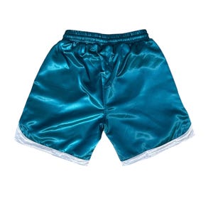 May include: Teal satin shorts with white trim. The shorts have an elasticated waistband and a shiny texture. The garment is designed for comfort and style. The shorts are approximately 30 cm in length.