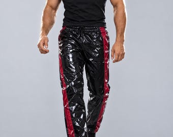 May include: Black short-sleeve t-shirt paired with shiny black pants featuring a vertical dark red stripe down each leg. The pants have a drawstring waistband and a glossy, reflective finish, worn with black sneakers.