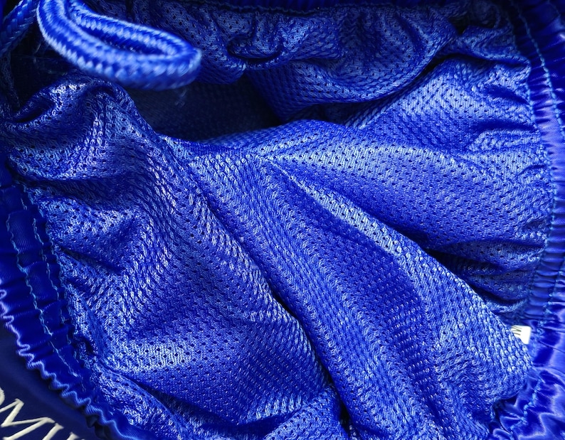May include: A pair of bright blue athletic shorts featuring a fine mesh lining throughout the interior. The garment includes a gathered elastic waistband with a matching blue drawstring cord visible at the top edge of the fabric.