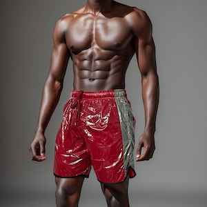 May include: A muscular man wearing red and gray athletic shorts. He is standing with his arms at his sides and looking directly at the camera.