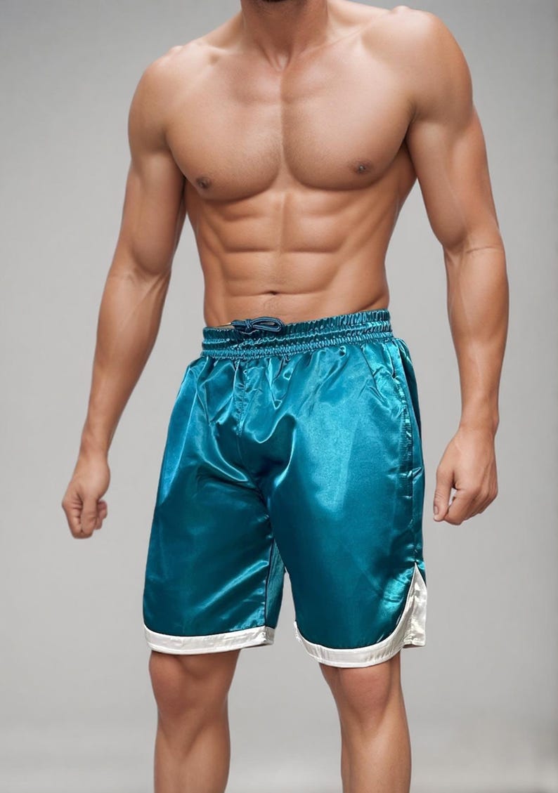 May include: Teal satin shorts with a drawstring waist and white trim. The shorts have a shiny, smooth texture and a relaxed fit. These athletic shorts are suitable for various activities.