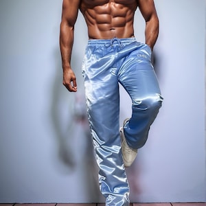 May include: Light blue satin pants with a drawstring waist and the letters "DMW" on the left leg. The pants are paired with white sneakers. The image shows athletic wear.