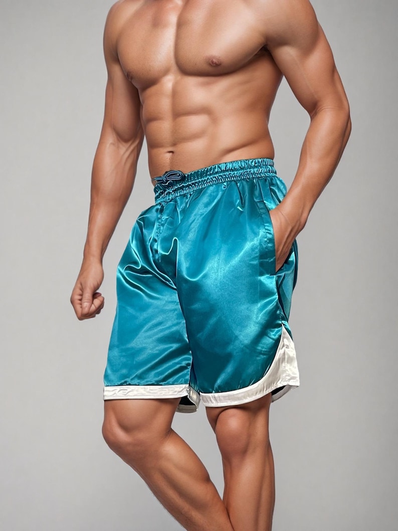 May include: Teal satin shorts with white trim. The shorts feature a drawstring waist and pockets. The fabric has a shiny appearance. The shorts are knee-length and appear to be athletic wear.