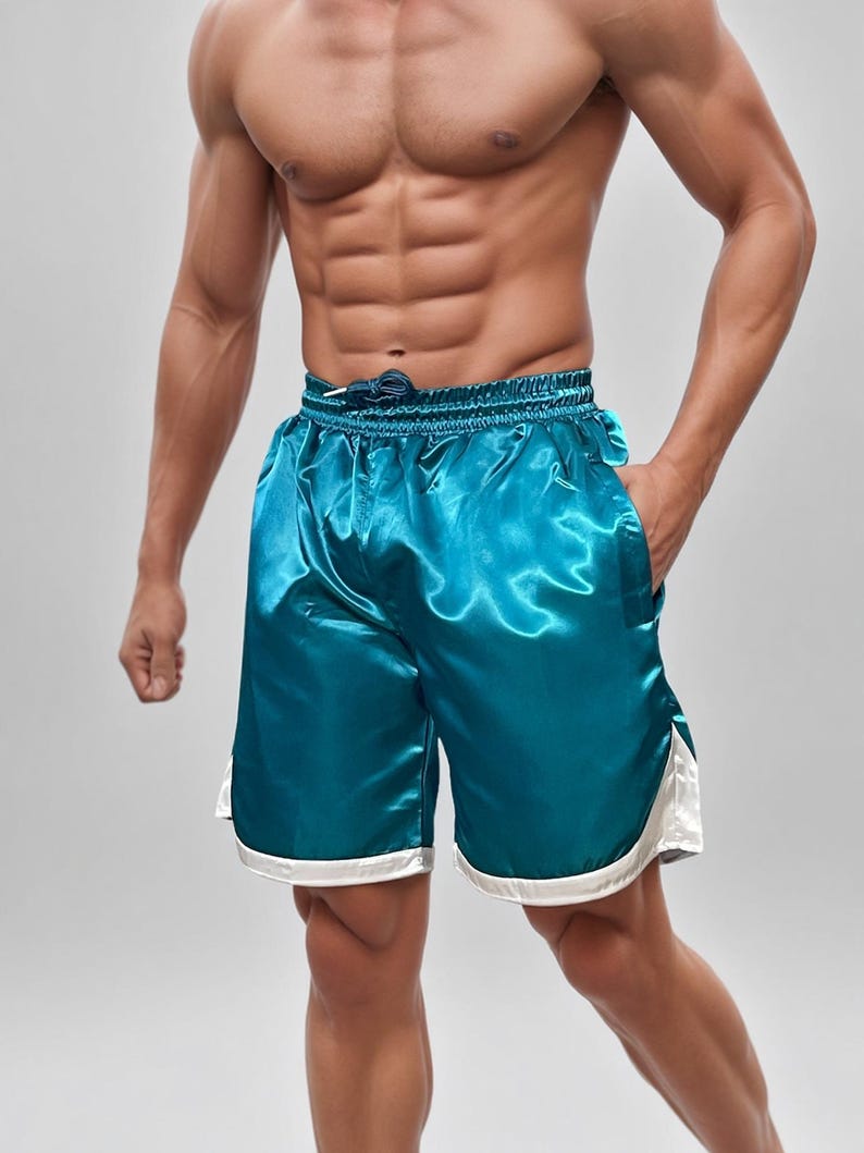 May include: Teal satin shorts with a drawstring waist and white trim. These athletic shorts have a shiny, smooth texture and a relaxed fit. The shorts are designed for comfort and style.