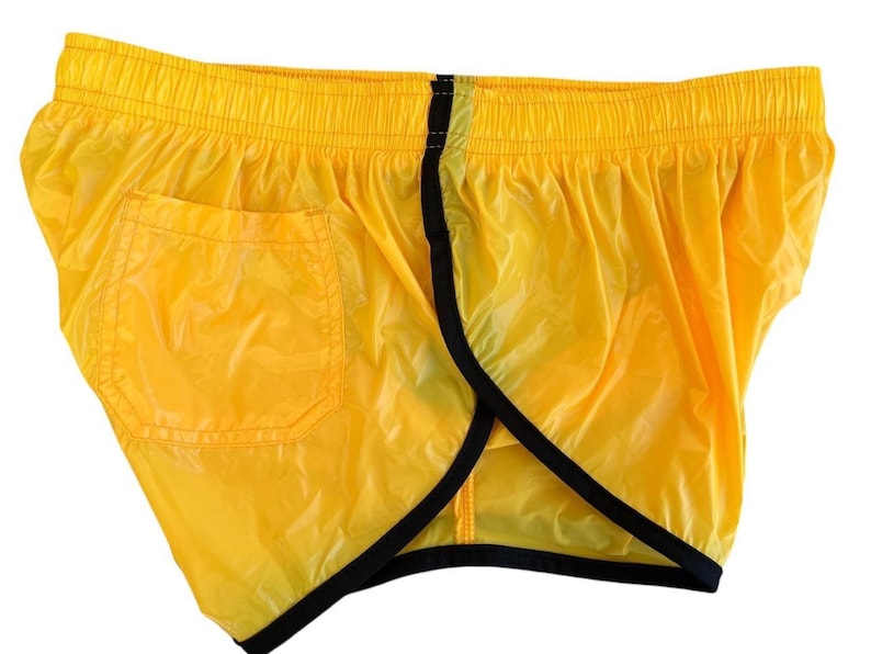 Op de afbeelding: Felge gele sportbroek met zwarte rand en &eacute;&eacute;n zak. De shorts hebben een elastische tailleband en zijn gemaakt van een lichtgewicht, enigszins transparant materiaal.
