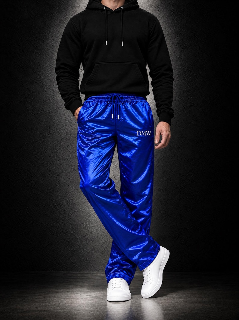 May include: Bright royal blue satin track pants featuring an elastic waistband with a drawstring and the text DMW embroidered in white on the upper left thigh. The pants have a straight-leg fit and a smooth, reflective finish.