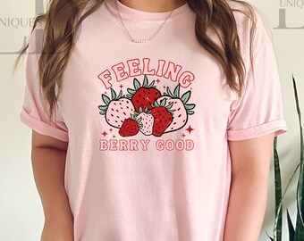 May include: Pink t-shirt with a graphic of strawberries and the text "Feeling Berry Good".