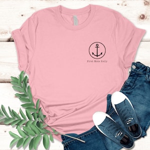 Puede incluir: Una camiseta rosa con un dise&ntilde;o de ancla negra y el texto "First Mate Kelly" en la parte delantera.