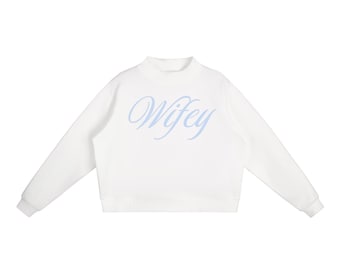 May include: White sweatshirt with a mock neck and long sleeves. The word "Wifey" is written in light blue script across the front. The sweatshirt is a casual, comfortable style.