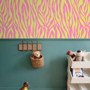 May include: A room with a vibrant pink and yellow zebra-striped wallpaper. Below, a teal wall features a woven coat rack, a wicker basket with a stuffed lion, a toy dinosaur, and a white bookshelf with stuffed animals and a book.