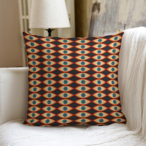 May include: A decorative throw pillow with a repeating pattern of stylized eyes in shades of orange, blue, and yellow on a dark background.