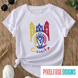 Puede incluir: Camiseta blanca con un diseño gráfico colorido de una iglesia con el texto "Chinita" debajo.