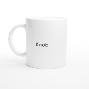 Könnte beinhalten: Eine weiße Keramiktasse mit gebogenem Henkel. Das Wort "Knob" ist schwarz auf der Oberfläche der Tasse zentriert gedruckt. Die Tasse steht vor einem weißen Hintergrund.
