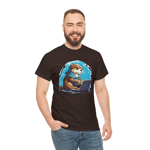 May include: A brown t-shirt featuring a cartoon otter wearing a blue scarf and using a laptop computer. The otter is sitting in a blue and white circle against a white background.