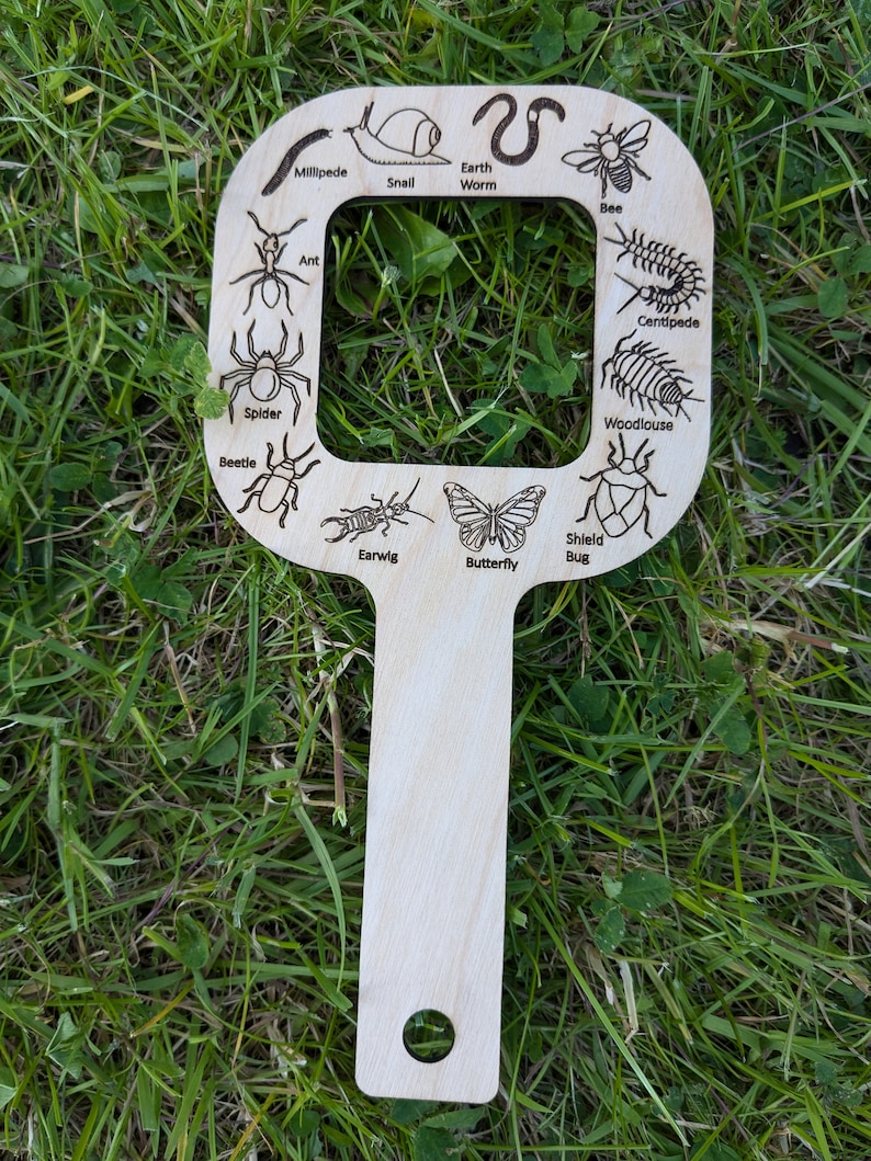 May include: A wooden bug identification tool with a handle and a frame with cutouts of different bugs, including a bee, centipede, butterfly, and beetle. The tool is labelled with the names of each bug.