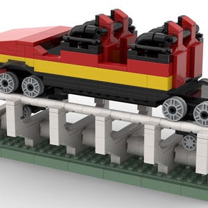 May include: A red and yellow Lego roller coaster car with black seats and wheels, on a white and grey track with green base plates.