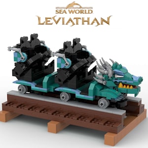 May include: A Lego model of the Sea World Leviathan roller coaster. The coaster is green and blue with a dragon head at the front. The coaster is on a brown wooden track.