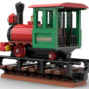 May include: A red and green toy train engine with a black chimney and wheels. The engine has a green cab with a sign that reads "C.R. COURAGEOUS". The train is on a track made of brown and black LEGO bricks.