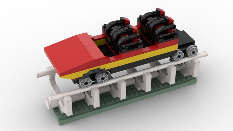 May include: A red, yellow and black Lego roller coaster car with black wheels and a white track. The car is on a green base with white supports.