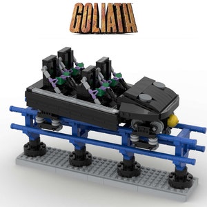 Könnte beinhalten: Ein schwarzer Lego-Achterbahnzug mit lila und grünen Sitzen, einem gelben Licht und blauen Schienen. Der Zug steht auf einem grauen Sockel mit dem Wort "GOLIATH" in braunen Buchstaben darüber.