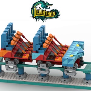 May include: A Lego model of a roller coaster train with blue, orange, and red seats. The train is on a green track and has a blue and yellow front section with the word "Leviathan" in green letters.