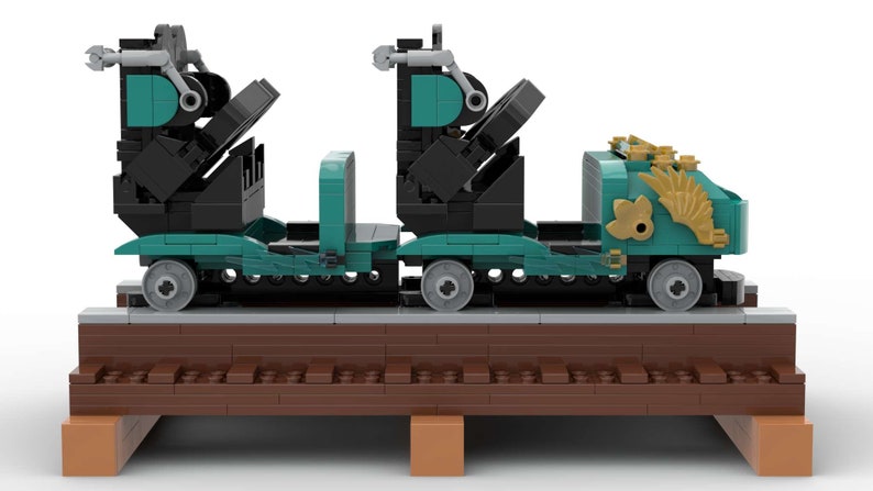 K&ouml;nnte beinhalten: Ein t&uuml;rkisfarbener und schwarzer Lego-Zugwagen mit goldenen Akzenten. Der Wagen hat zwei Sitze und steht auf einem braunen Gleis.