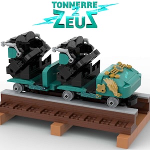 May include: A Lego model of a roller coaster train with two black seats and a teal and gold car. The car has a lightning bolt and wings on the side. The train is on a wooden track. The text "TONNERRE 2 ZEUS" is above the train.