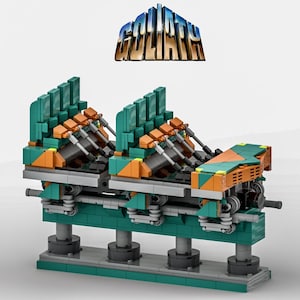 Puede incluir: Un modelo de bloques de construcción de un vagón de montaña rusa con componentes en color verde azulado, naranja y gris, con la palabra GOLIATH en letras metálicas azules y doradas sobre la estructura. Incluye asientos, ruedas y vigas detalladas.